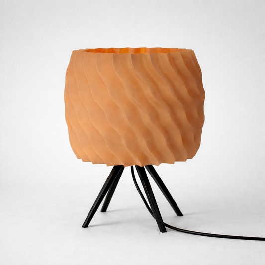 Table lamp with orange textured shade and black metal base on a white background