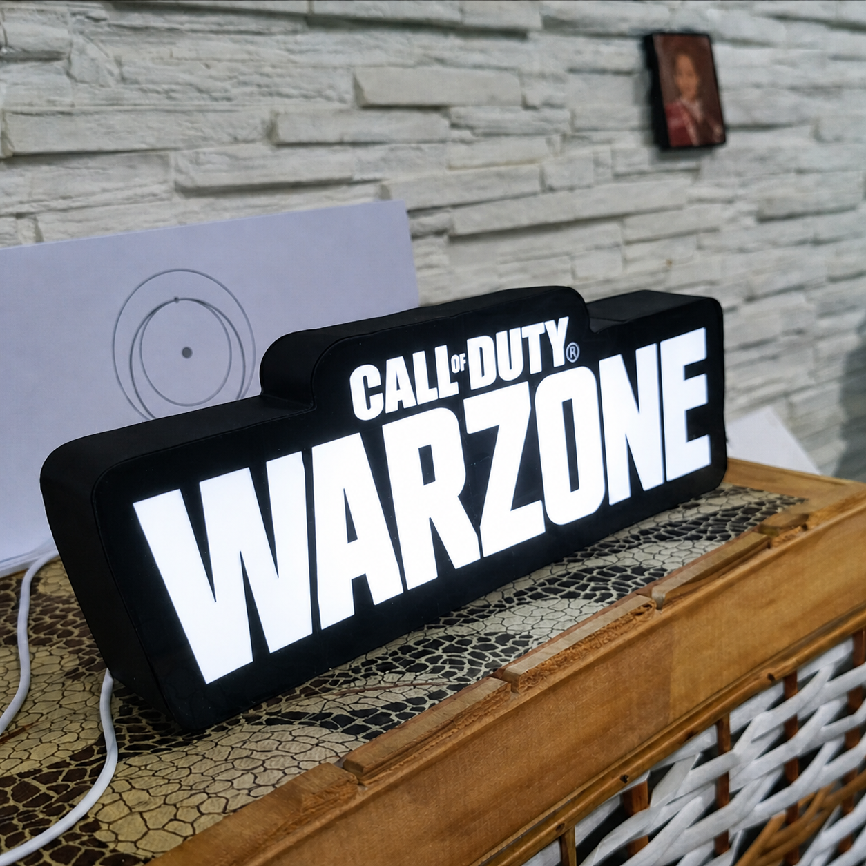Call of Duty Warzone sign on a wooden surface with a stone wall background
