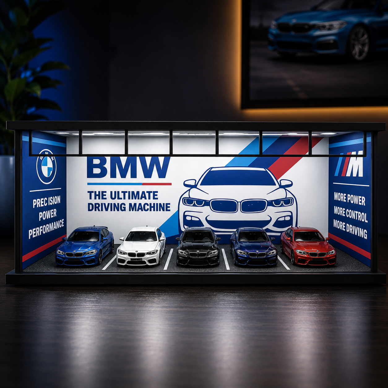 A BMW-branded display case or miniature showroom featuring five small cars in front of a large BMW logo and car graphic, with BMW text on the side panels.