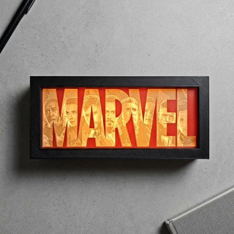 Framed Marvel logo with a pen and notebook on a gray surface