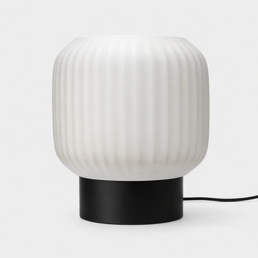 Table lamp with ribbed white shade and black base on a white background
