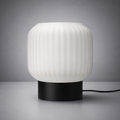 Table lamp with ribbed white shade and black base on a gray background